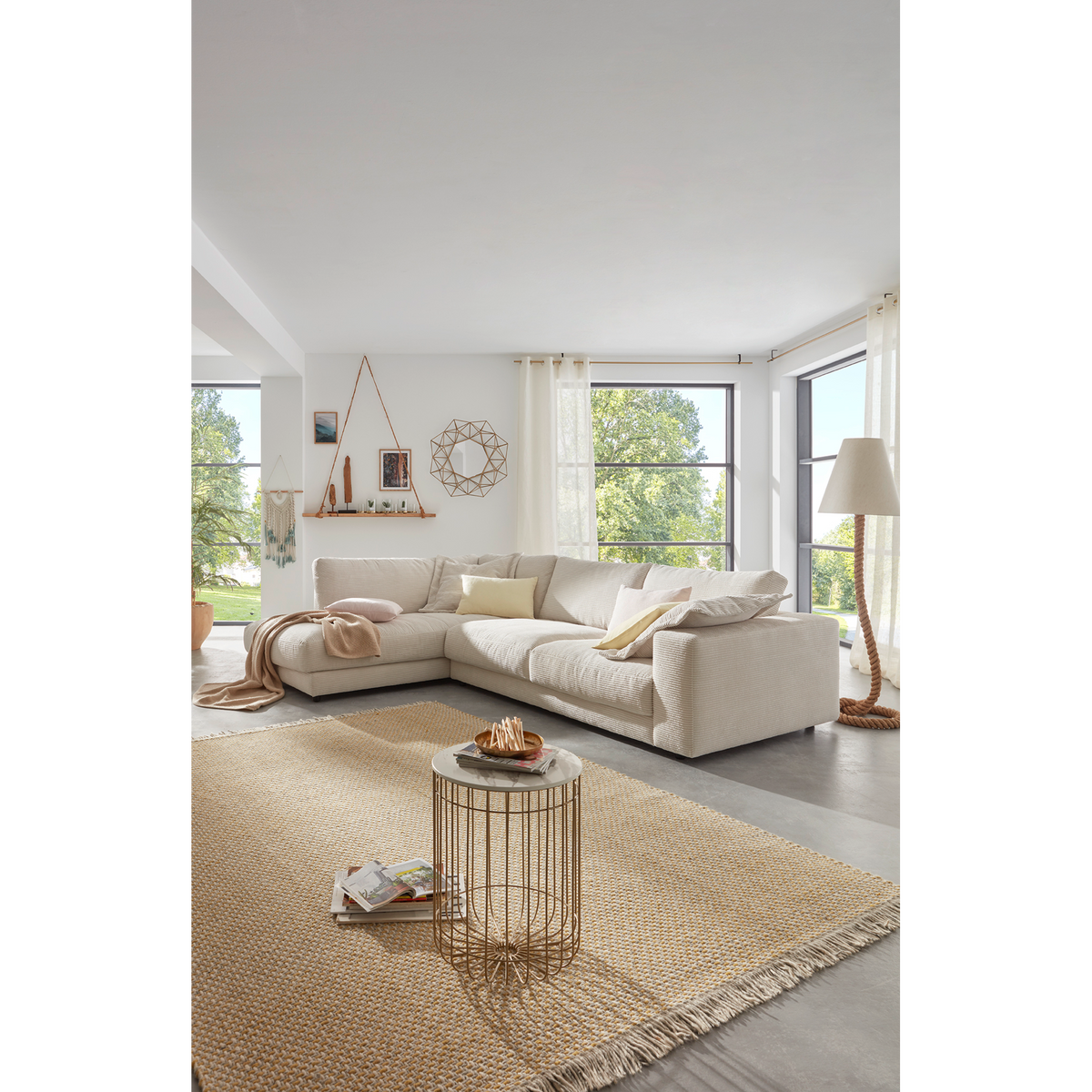 Candy Ecksofa Cord Snow im hellen Wohnzimmer mit Naturteppich, Couchtisch und großen Fenstern