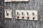 HAKU Möbel Schlüsselboard aus Massivholz Motiv Baumscheibe und Schriftzug in Grau