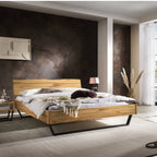Modernes Holzbett mit schwarzem Metallgestell in hellem Schlafzimmer mit dunkler Akzentwand